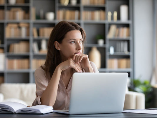 A woman distracted while working on a laptop.