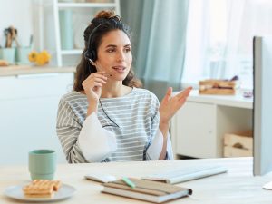 Fully engaged woman, talking through headset looking at computer monitor
